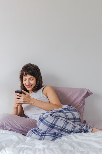Donna sul letto con smartphone