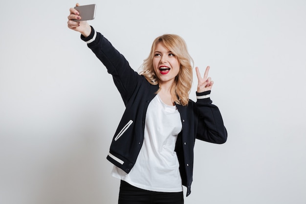 Donna sveglia sorridente che prende la foto del selfie sullo smartphone