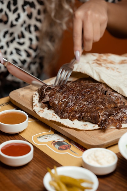 donna taglio bistecca di agnello su focaccia con maionese e ketchup