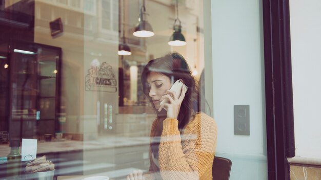 Donna triste che parla sul telefono nella caffetteria