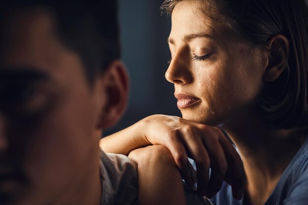 Donna triste che piange con gli occhi chiusi mentre si appoggia sulla spalla del ragazzo