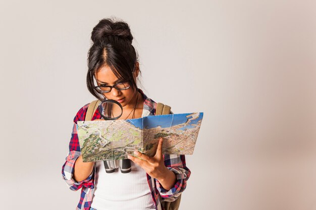 Donna turistica con lente di ingrandimento per esaminare la mappa