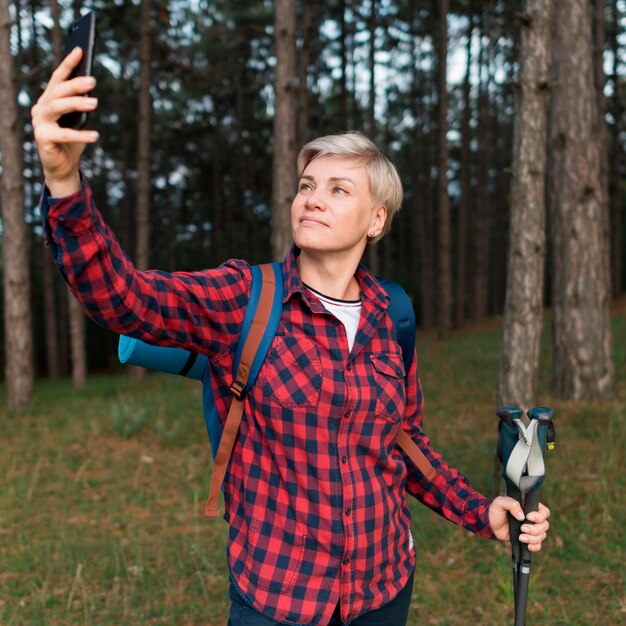 Donna turistica senior che prende selfie nella foresta