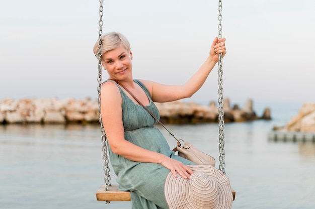 Donna turistica senior di smiley alla spiaggia nell'oscillazione