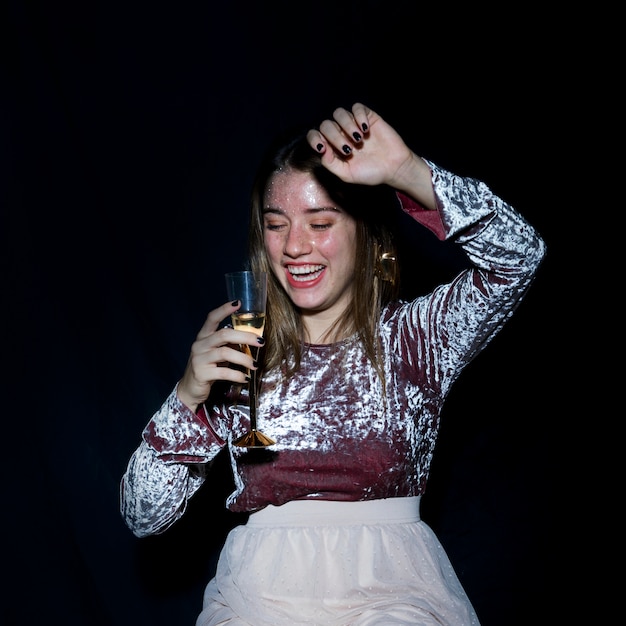 Donna ubriaca in piedi con un bicchiere di champagne