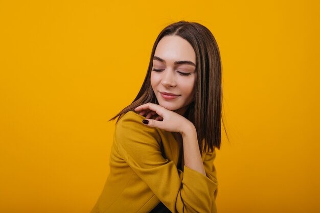 Donna vaga in abiti eleganti in posa con un sorriso gentile. Ritratto di ragazza bianca alla moda con capelli castani.