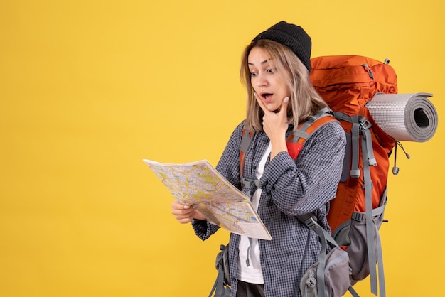 donna viaggiatrice con zaino guardando la mappa con grande sorpresa
