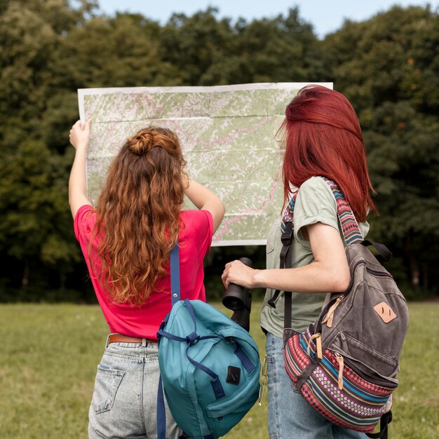 Donne a metà tiro con il binocolo e la mappa in natura