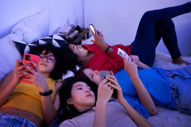 Donne ad alto angolo a letto con gli smartphone