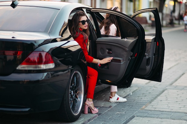 Donne alla moda che escono dall'auto.