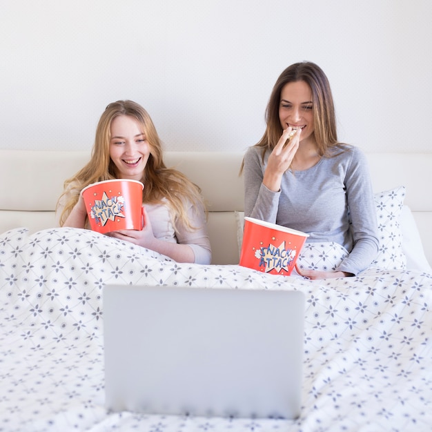 Donne allegre che guardano film a letto