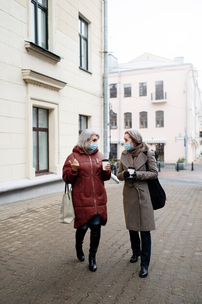 Donne anziane a tutto campo che camminano con le maschere