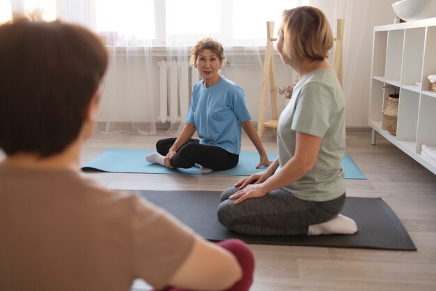 Donne anziane che fanno esercizi insieme a casa e parlano