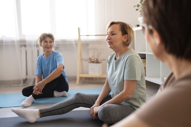 Donne anziane che fanno yoga a casa e parlano tra loro