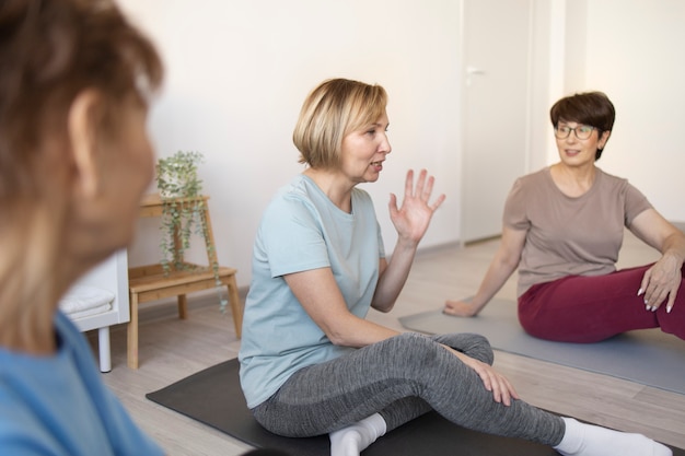 Donne anziane che fanno yoga a casa e parlano tra loro