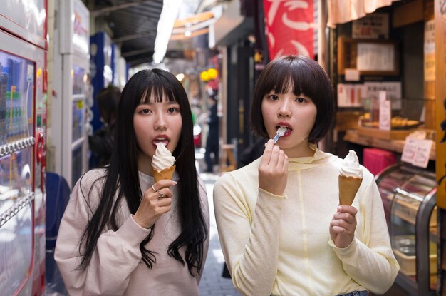 Donne asiatiche del colpo medio che mangiano il gelato