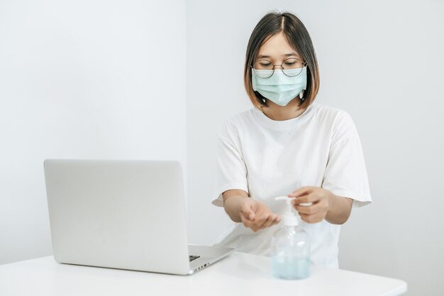 Donne che indossano camicie bianche che premono il gel per lavarsi le mani e pulirle.