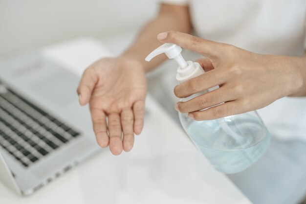 Donne che indossano camicie bianche che premono il gel per lavarsi le mani e pulirle.
