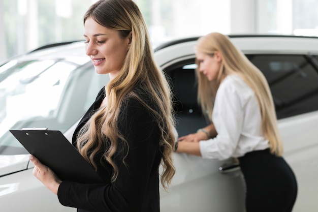 Donne che osservano via nello showroom di automobili