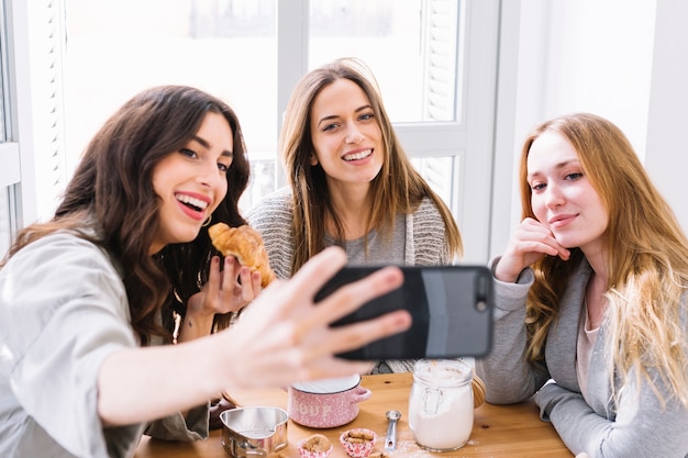 Donne che posano per selfie con pasticceria