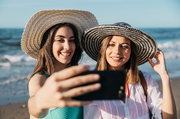 Donne che prendono selfie in spiaggia
