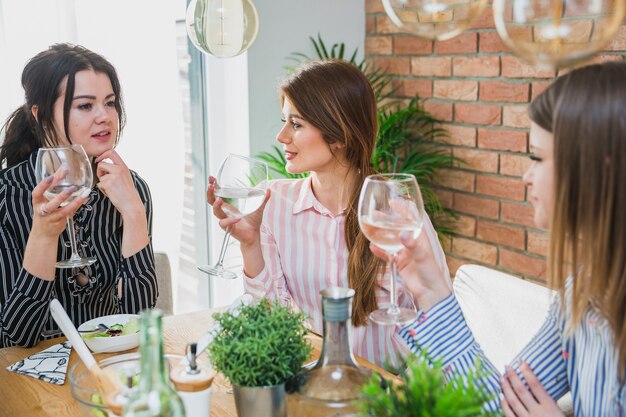 Donne che si siedono al tavolo tenendo i bicchieri