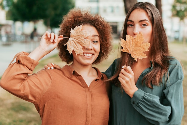 Donne che tengono le foglie secche in autunno