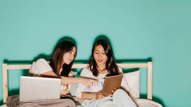 Donne che utilizzano laptop e tablet a letto