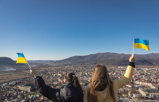 Donne con bandiere dell'ucraina sullo sfondo del cielo e delle montagne