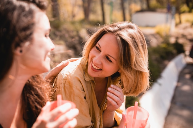 Donne con bevande che ridono e chiacchierano