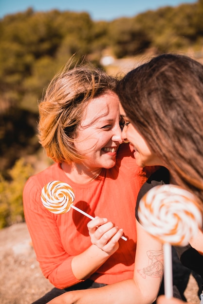 Donne con lecca-lecca che toccano il naso