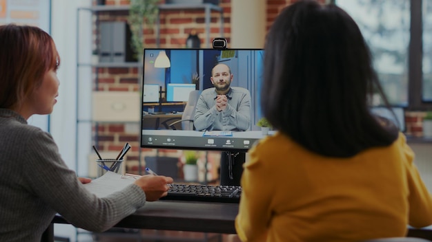 Donne d'affari che partecipano a un colloquio di lavoro online in videochiamata, utilizzando il computer per parlare con il candidato dell'occupazione. I colleghi intervistano il candidato sul contratto di assunzione in teleconferenza a distanza.