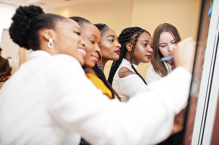 Foto gratuito donne d'affari che puntano sul vetro con note di carta colorate gruppo eterogeneo di dipendenti di sesso femminile in abbigliamento formale che utilizzano adesivi