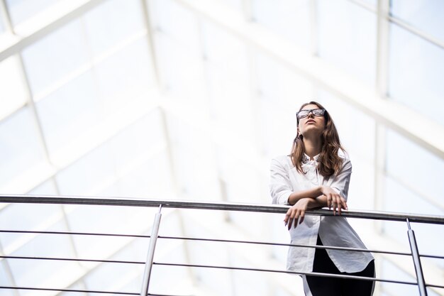 Donne d'affari di successo in piedi guardando attraverso il balcone nel centro ufficio moderno vestite in maglietta bianca