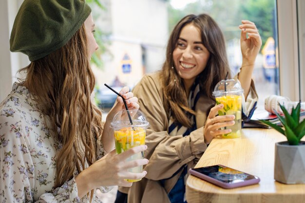 Donne del colpo a metà con bevande fresche che parlano nella caffetteria