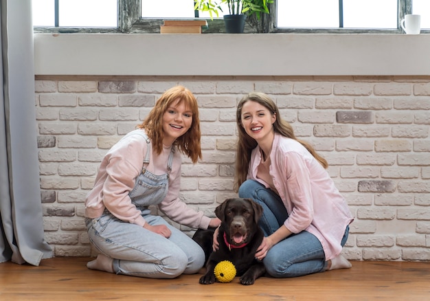 Donne del colpo pieno che posano con il cane