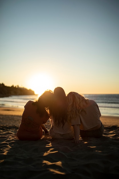 Donne del colpo pieno che si siedono sulla spiaggia