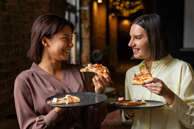 Donne del piano medio che mangiano pizza deliziosa