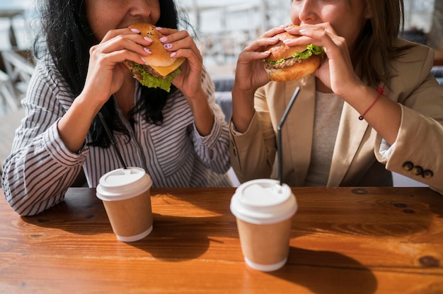 Donne del primo piano che mangiano hamburger