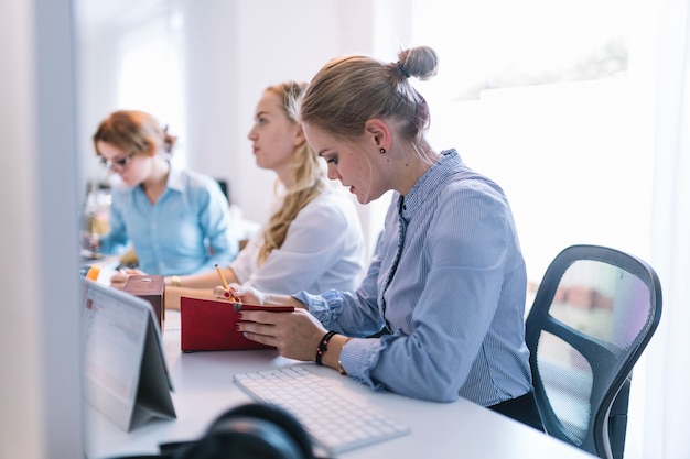 Donne di affari che si siedono in una fila che funziona nell&#39;ufficio