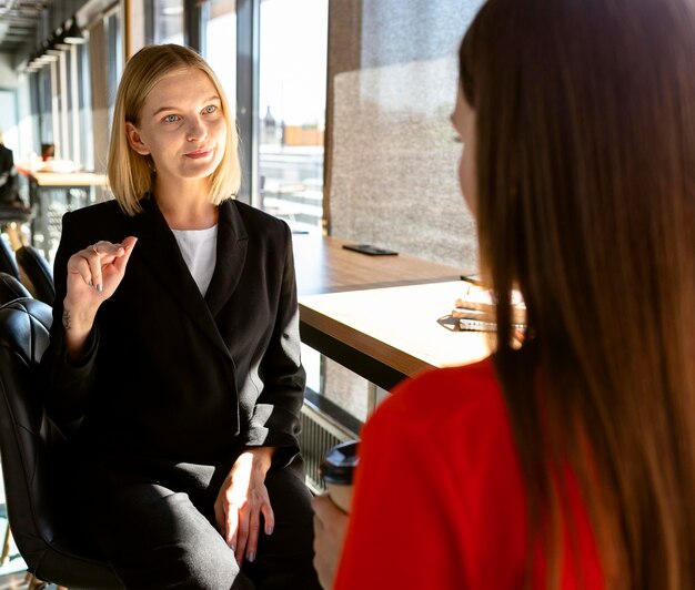 Donne di affari che utilizzano il linguaggio dei segni al lavoro per comunicare tra loro