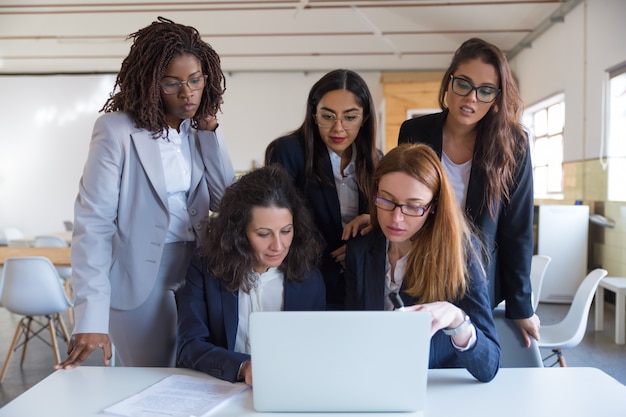 Donne di affari messe a fuoco che utilizzano computer portatile nell'ufficio