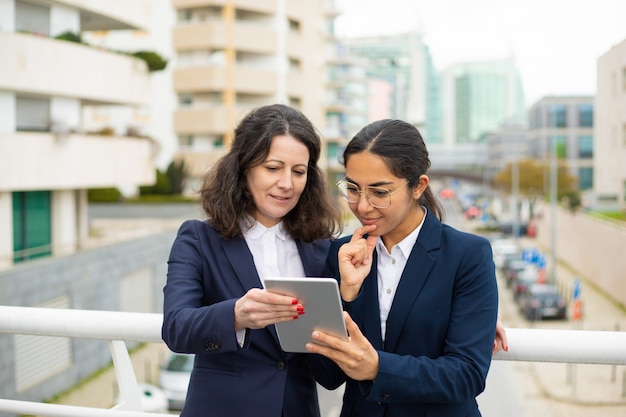 Donne di affari sorridenti che per mezzo del pc della compressa