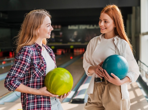 Donne di smiley che tengono le sfere di bowling variopinte