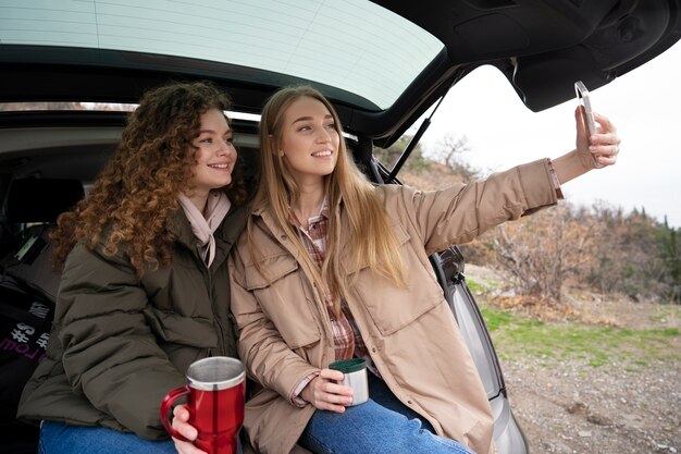 Donne di smiley di vista laterale nel bagagliaio dell'auto