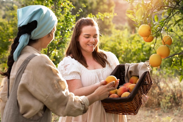 Donne di tiro medio che raccolgono frutta