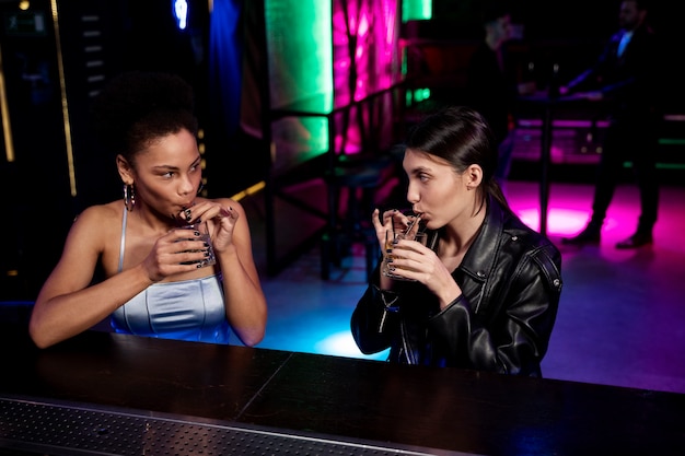 Donne di tiro medio con drink al bar