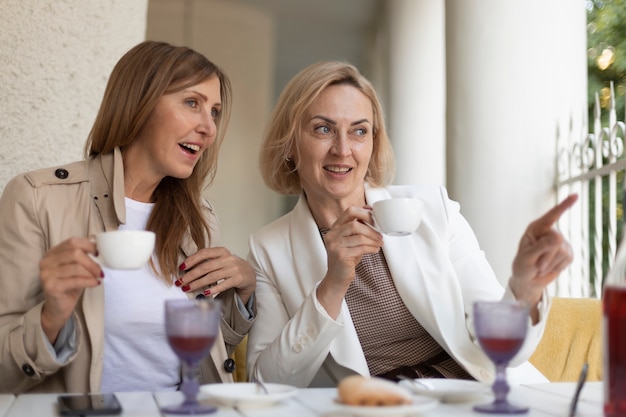 Donne di tiro medio con tazzine da caffè