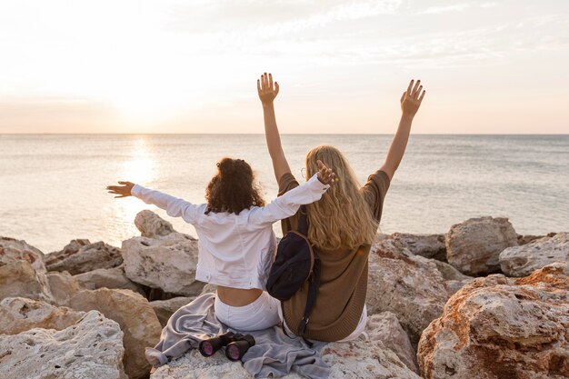 Donne di vista posteriore che si siedono sulla roccia