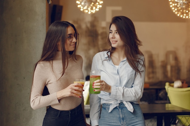 Donne eleganti che stanno in un caffè e che bevono un cocktail